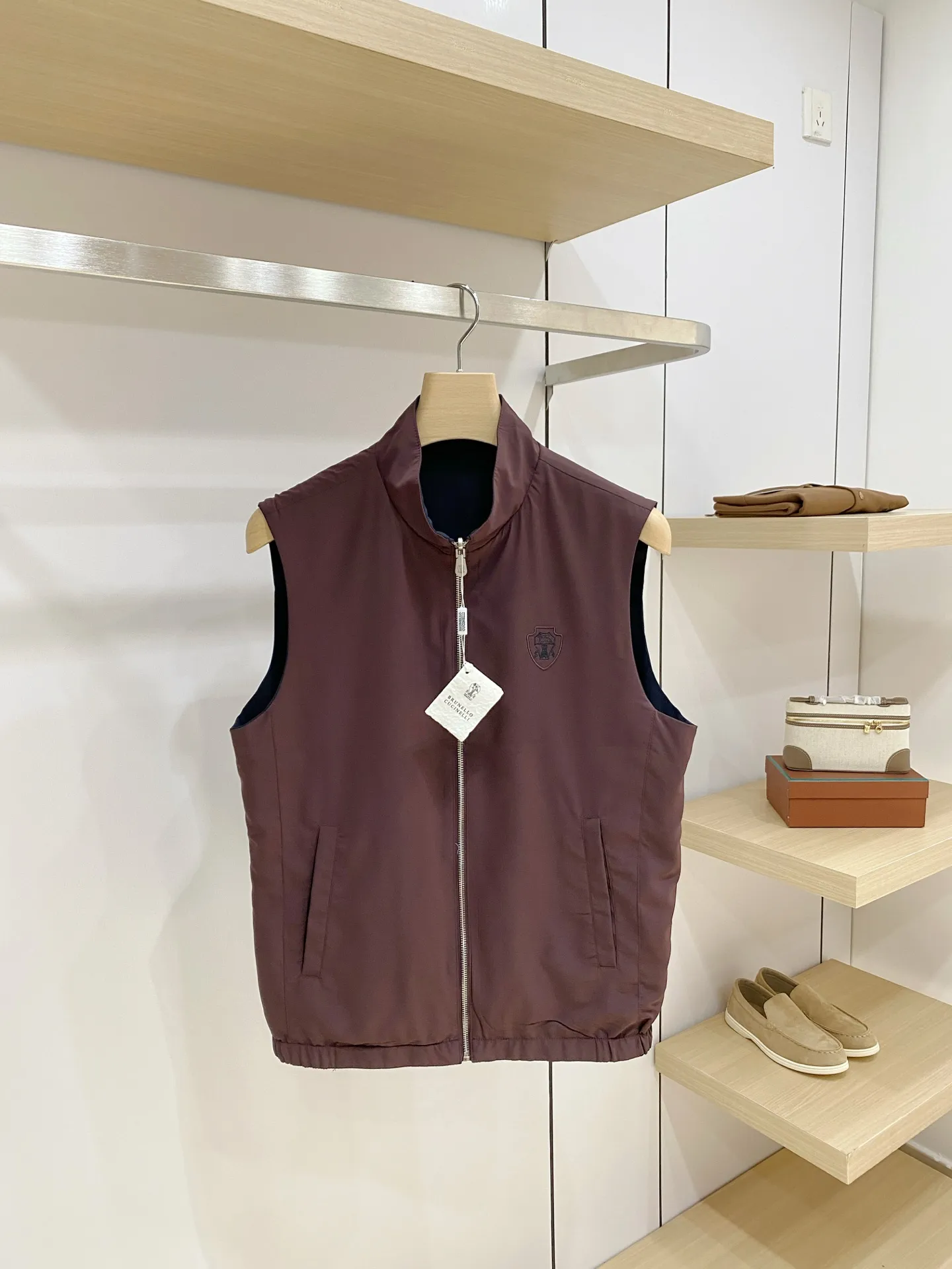 BC Reversible Stand Collar Men's Vest Style: Simple stand collar sleeveless vest, fitted straight cut, elastic hem at the hem, not tight or pressing. The sleeveless design does not restrict arm movement and can be worn both inside and outside. It is suitable for layering shirts, sweaters, and long-sleeved T-shirts. It can be used for business, leisure, and daily travel. It is highly tolerant to a variety of body shapes. Fabric: Made of high-density anti-wrinkle functional fabric, it feels smooth and crisp, has certain windproof properties, is not easy to wrinkle, and is easy to care for. The front and back sides are in different colors, the fabric has the same texture, is light and moderate, and is suitable for the transitional seasons from spring to autumn. Craftsmanship: The metal zipper is smooth and durable, and the zipper pockets on both sides ensure safe and secure placement of items; the exquisite shield-shaped embroidered logo on the chest is low-key and luxurious. The whole piece is neatly cut, the edges and corners are clean, and the workmanship inside and outside is equally exquisite. Lining details (double-sided structure) The two sides can be worn directly outside without a separate lining cloth, and the colors on the two sides are in contrast to each other. The splicing and binding are precision lock-stitched, with no excess threads, and the seams are smooth and snug; the fabric feels delicate, smooth to put on and take off, and will not scratch the inner clothing; the hem is elastic and solid, and will not be easily deformed after repeated pulling. Both sides can be worn independently as fronts to achieve two outfit effects. Color: Cream White/burgundy, caramel/beige gray, Black/Navy Blue, Navy Blue/burgundy, multiple sets of double-sided contrasting colors, the tone is calm and high-end, suitable for all kinds of bottoms. Sizes: M‑4XL